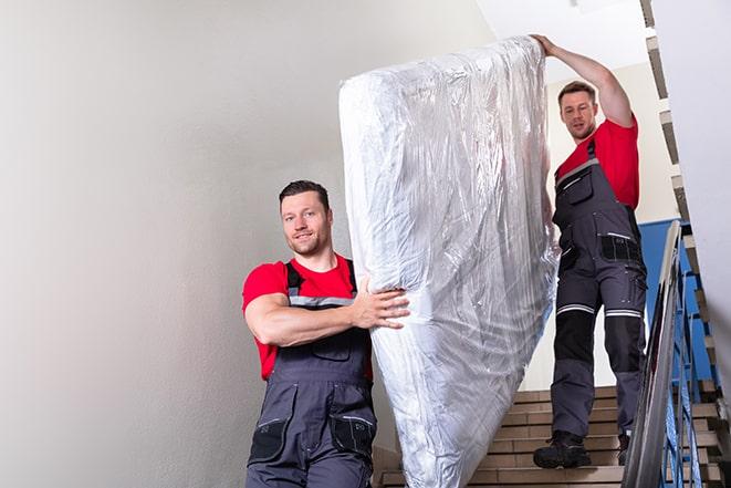 two workers lifting a box spring out of a bedroom in Grantham